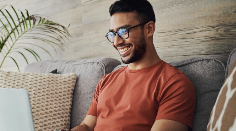 A smiling young man is working on his laptop