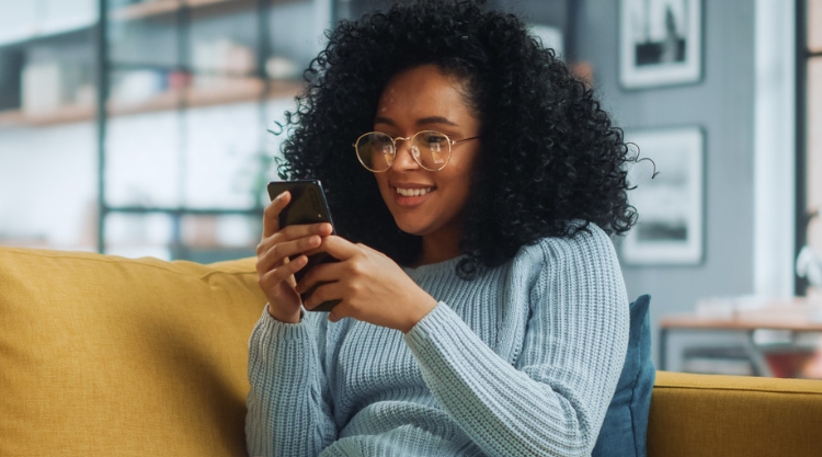 A smiling young woman uses her mobile device