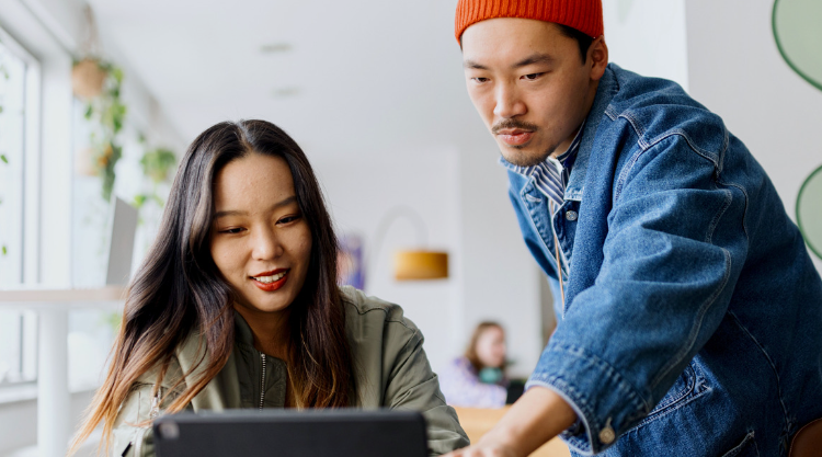 A young man and young woman collaborate on a laptop computer