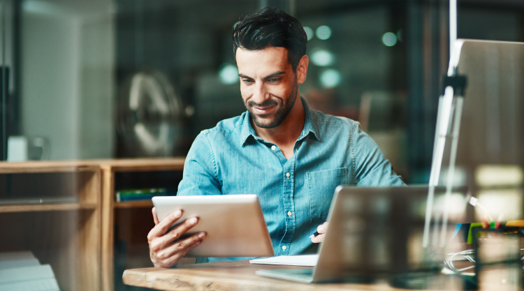 A man uses a mobile device and laptop while working