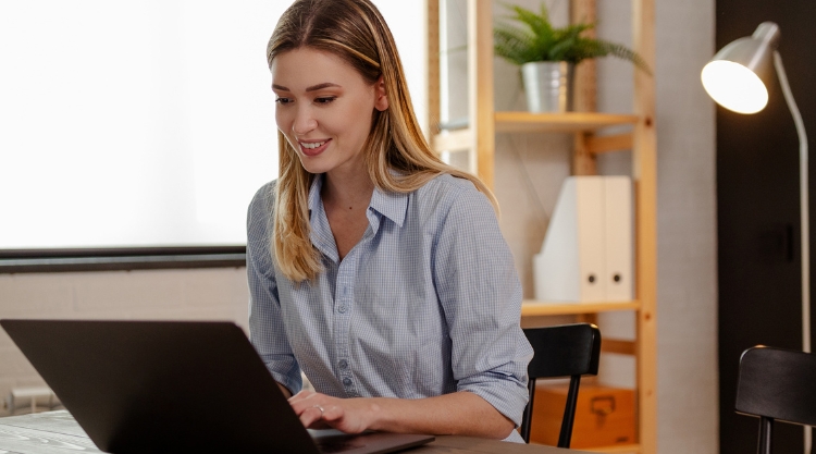 Smiling woman works on her laptop computer