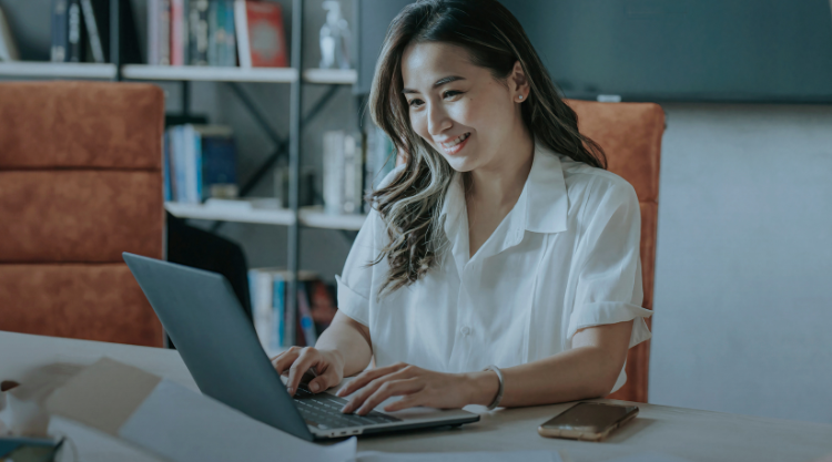 Woman smiling while scrolling on laptop