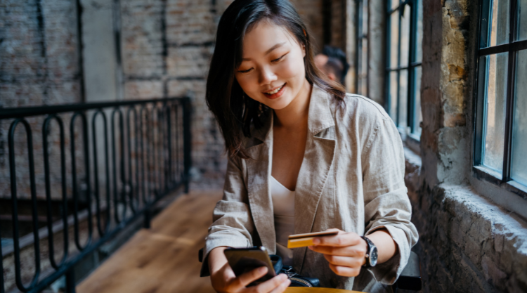 A smiling young woman uses her mobile device