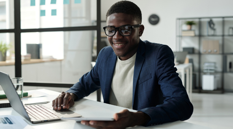 A smiling young man uses his laptop computer