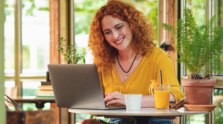 A smiling woman uses her laptop computer