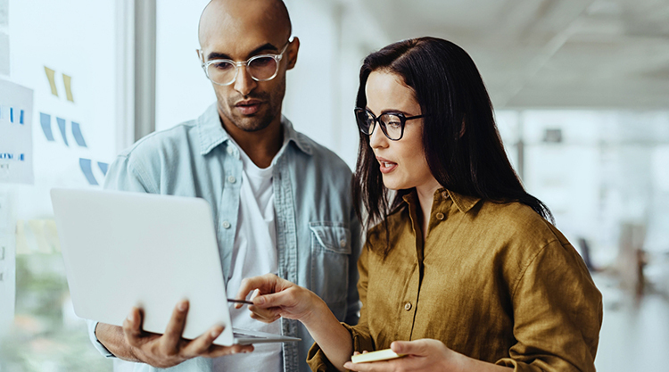 A man and woman collaborate on their laptop computer